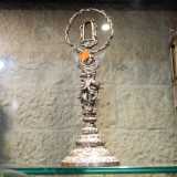Ad attirare la nostra attenzione c�� anche un reliquiario a forma di corona d�argento intrecciata e retta da un piede in ottone sormontato da figure umane e angeliche